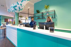 two people sitting at a counter in a store at the niu Wave - Apartments in Karlsruhe