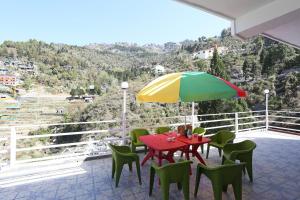 d'une terrasse avec une table, des chaises et un parasol coloré. dans l'établissement OYO The Mountain Dream, à Mussoorie