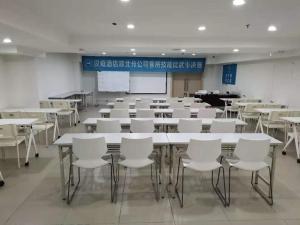 a classroom with white tables and white chairs at Hanting Hotel Wuhan Guanggu Plaza in Liufangling