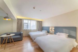a hotel room with two beds and a table at Hanting Hotel Wuhan MinHang Xiaoqu in Wuhan