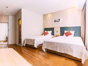 two beds in a hotel room with wooden floors at Hanting Hotel Lvliang Citizen Square in Luliang