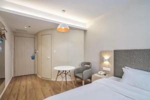 um quarto com uma cama, uma cadeira e uma mesa em Hanting Hotel Nanjing Daishandong Laiao Nancheng em Xishanqiao