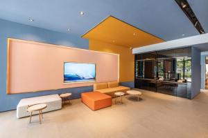 a lobby with a couch and chairs and a large screen at Hanting Hotel Suzhou Yuanqu Jinji Lake in Houlujiaku