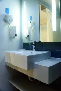 a bathroom with a white sink and a mirror at Hanting Hotel Linyi Mengshan Avenue in Linyi