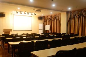 a conference room with tables and chairs and a screen at Hanting Hotel Linyi Mengshan Avenue in Linyi