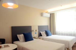 a hotel room with two beds with blue pillows at Hanting Hotel Linyi Mengshan Avenue in Linyi