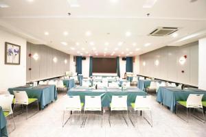 a conference room with tables and chairs and a screen at Hanting Hotel Jinan High-tech Zone Wanda Plaza in Hongjialou