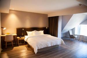 a bedroom with a large white bed and a desk at Hanting Premium Hotel Youjia Dengfeng Terminal in Dengfeng
