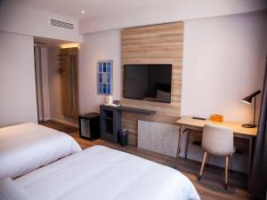 a hotel room with two beds and a desk with a television at Hanting Premium Hotel Youjia Dengfeng Terminal in Dengfeng