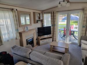 a living room with a couch and a television at Sunnyside lodge in Cirencester