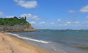 a beach with a house on a hill next to the ocean at Ji Hotel Yantai Penglai Zhonglou Dong Road in Penglai