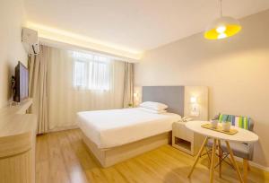 a bedroom with a white bed and a table at Hanting Hotel Ulanhot Railway Station in Ulanhot