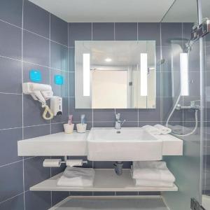 a bathroom with a white sink and a mirror at Hanting Hotel Ulanhot Railway Station in Ulanhot