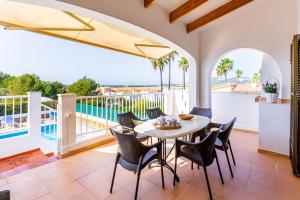 a dining room with a table and chairs on a balcony at Villa Ponent in Son Bou