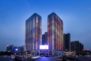 Ji Hotel Changde Tianrun Plaza في تشانغده: مبنيان طويلان في مدينة في الليل