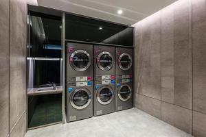 蘇州市にあるHanting Hotel Suzhou Guanqian Street Centerのランドリールーム(洗濯機4台、シンク付)