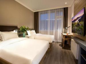 Hanting Premium Hotel Jinan Shandong University Central Campus في Licheng: غرفة فندقية بسريرين ونافذة