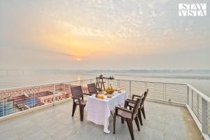 a table on a balcony with a view of the water at StayVista at The Ganga House - Holy River Varanasi in Varanasi