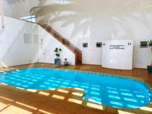 a large blue swimming pool in a building with a staircase at Camere da Letto ON-THE-BEACH Self Catering in Swakopmund