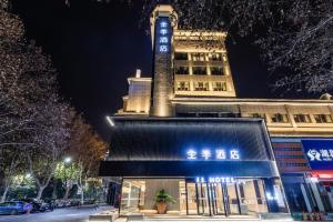 un edificio con una torre de reloj en una calle por la noche en Ji Hotel Xiangyang Tangcheng Shengli Street en Xiangyang