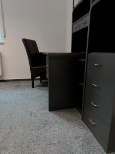 a black dresser and a chair in an office at City-Residenz Ge-Buer in Gelsenkirchen