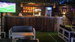 a bar with a tv and a man standing behind it at Kosam Global Hotel and Suites in Uyo