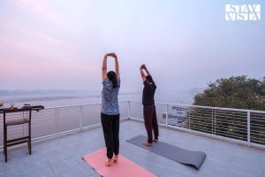 duas pessoas estão a fazer yoga num telhado em StayVista at The Ganga House - Holy River Varanasi em Varanasi