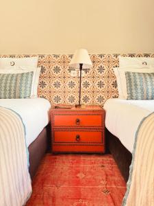 an orange suitcase sitting between two beds in a room at Riad Abracadabra in Marrakech