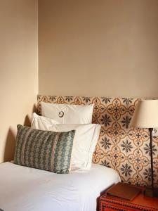a bed with white pillows and a headboard with a lamp at Riad Abracadabra in Marrakech