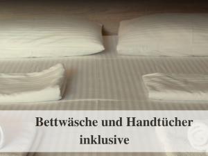 a bed with white sheets and two pillows on it at Waldstrandnest mit Weitblick in Timmendorfer Strand +8 photos