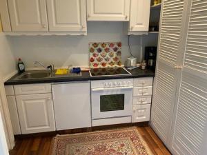 a kitchen with white cabinets and a stove and a sink at Waldstrandnest mit Weitblick in Timmendorfer Strand