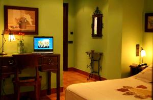 a bedroom with a bed and a desk with a laptop on it at Hotel Baviera in Linares