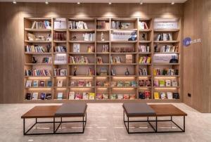 deux bancs devant une étagère avec des livres dans l'établissement Hanting Premium Hotel Youjia Wuhan Etouwan Metro Station, à Wujiashan