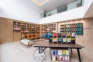 a library with book shelves and a table with books at Hanting Premium Hotel Youjia Changchun Shuangyang Yiyang Building 