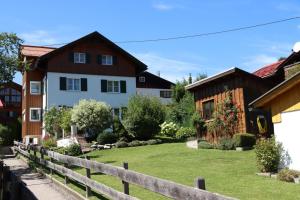 uma casa com uma cerca em frente a um quintal em Allgäu Oase - fewo-badhindelang em Bad Hindelang