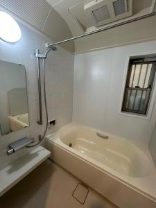 een witte badkamer met een bad en een spiegel bij CROWN 越中島 in Tokyo