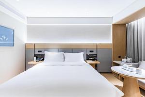 a bedroom with a large bed and a table at Ji Hotel Nanjing Xianlin Center in Dongchanglin