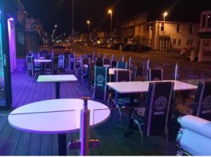 a row of tables and chairs on a street at night at Tamarind Cove & Barrons Hotel in Blackpool