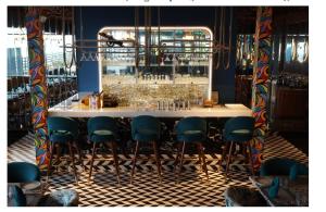 a bar with blue bar stools in a room at Mastiff Hotel Dhanbad in Dhanbād