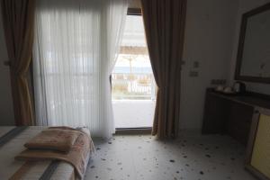 a bedroom with a bed and a large window at GLENN HOTEL& BEACH in Ayvacık