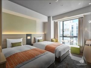 a hotel room with two beds and a window at Daiwa Roynet Hotel Osaka Sakaisuji Honmachi PREMIER in Osaka