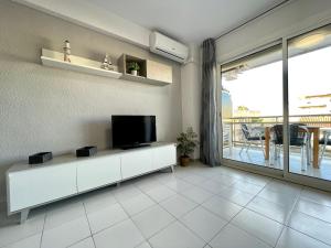 ein Wohnzimmer mit einem TV und einem Balkon in der Unterkunft Costa Daurada Apartaments - LA SIRENA in Salou