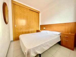 ein Schlafzimmer mit einem Bett und einer Holzwand in der Unterkunft Costa Daurada Apartaments - LA SIRENA in Salou