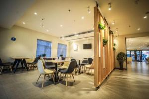 Hanting Hotel Shenyang Wanlian Metro Station في شنيانغ: قاعة اجتماعات مع طاولات وكراسي في مبنى