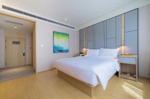 a bedroom with a large white bed in a room at Ji Hotel Dalian Railway Station in Dalian