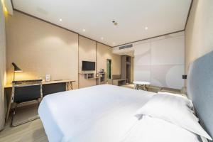 a bedroom with a large white bed and a desk at Hanting Hotel Shanghai Qingpu Caoying Road Metro Station in Qingpu