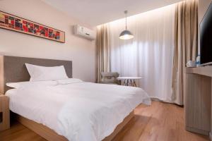 a bedroom with a large white bed and a window at Hanting Hotel Nanjing Hexi Jiqingmen Street in Nanjing