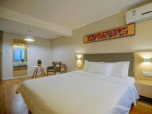 a bedroom with a large white bed and a table at Hanting Hotel Nanjing Hexi Jiqingmen Street in Nanjing