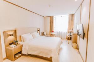 um quarto com uma grande cama branca e uma janela em Hanting Hotel Wenzhou Leqing Liushi Town em Hengdaiqiao