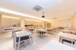 ein Esszimmer mit Tischen und Stühlen sowie eine Küche in der Unterkunft Ji Hotel Ningbo Yinzhou Impression City in Panhuo